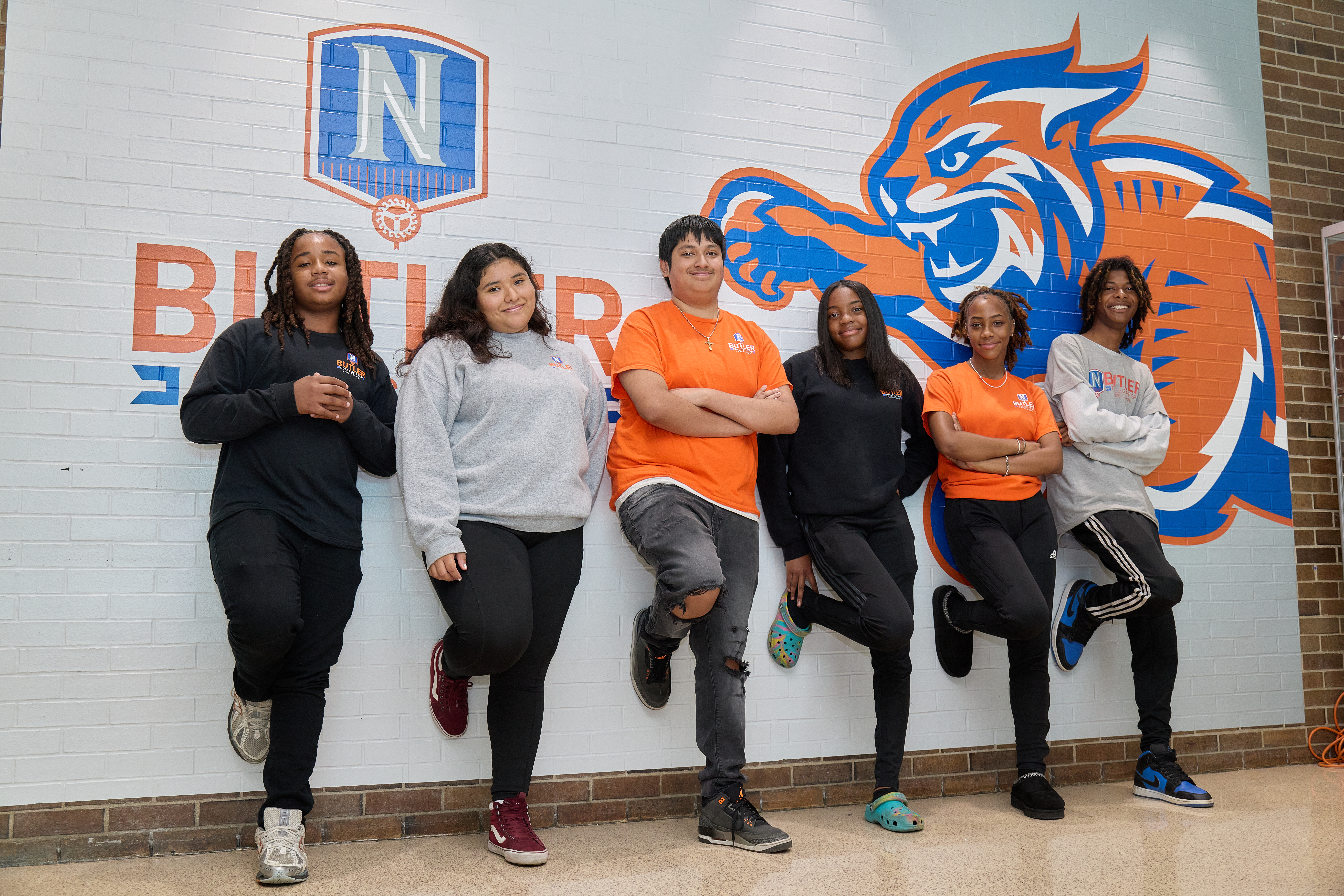 Proud college prep students from Chicago Butler campus standing by the wall with the school mascot and logo