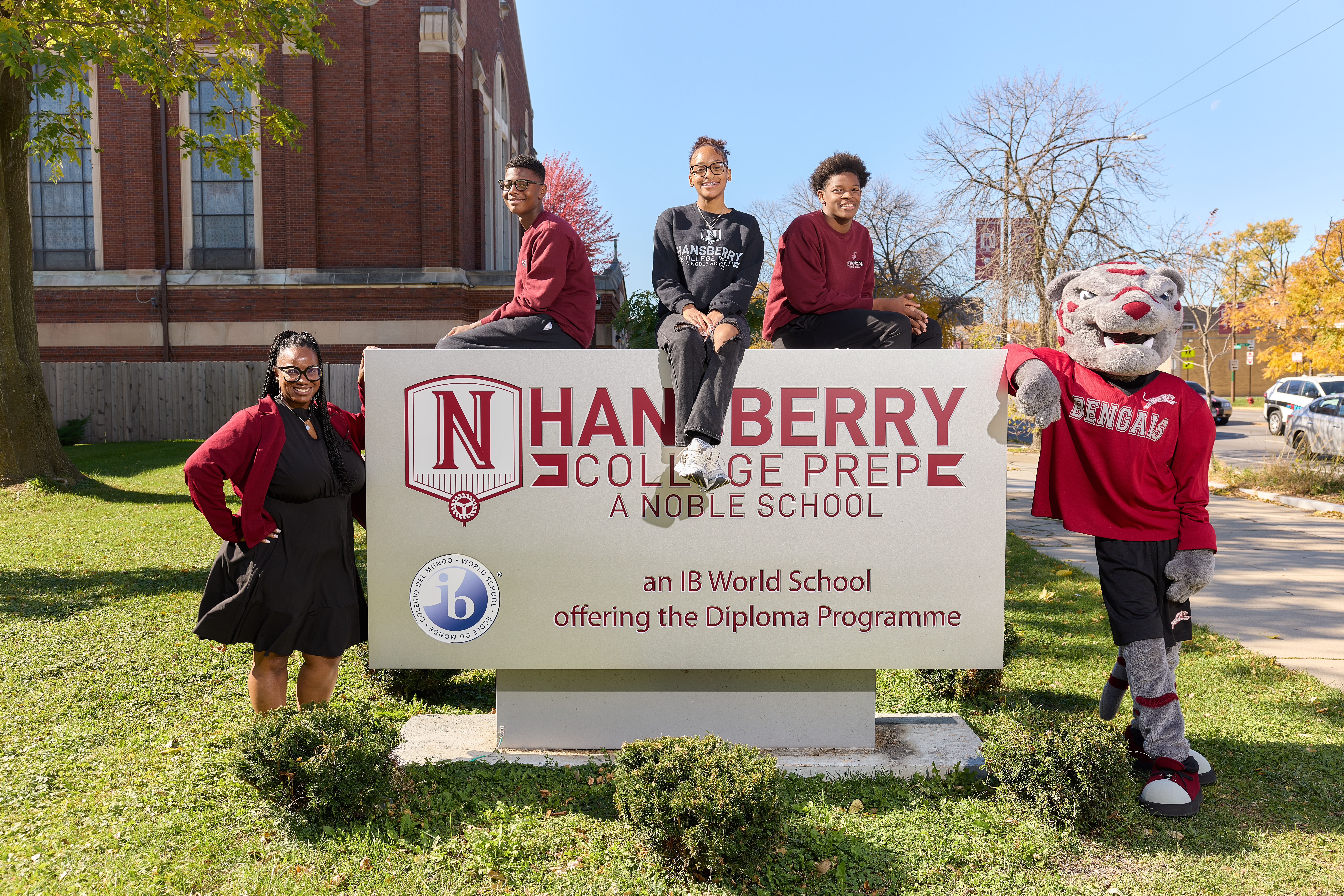 Hansberry University Prep students in Chicago posing outside with a teacher and school mascot