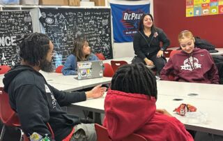 A group of ITW David Speer Academy students sit in a circle at classroom desks with a NAMI staff member. They are actively discussing something and look very comfortable and safe with the group.