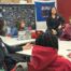 A group of ITW David Speer Academy students sit in a circle at classroom desks with a NAMI staff member. They are actively discussing something and look very comfortable and safe with the group.