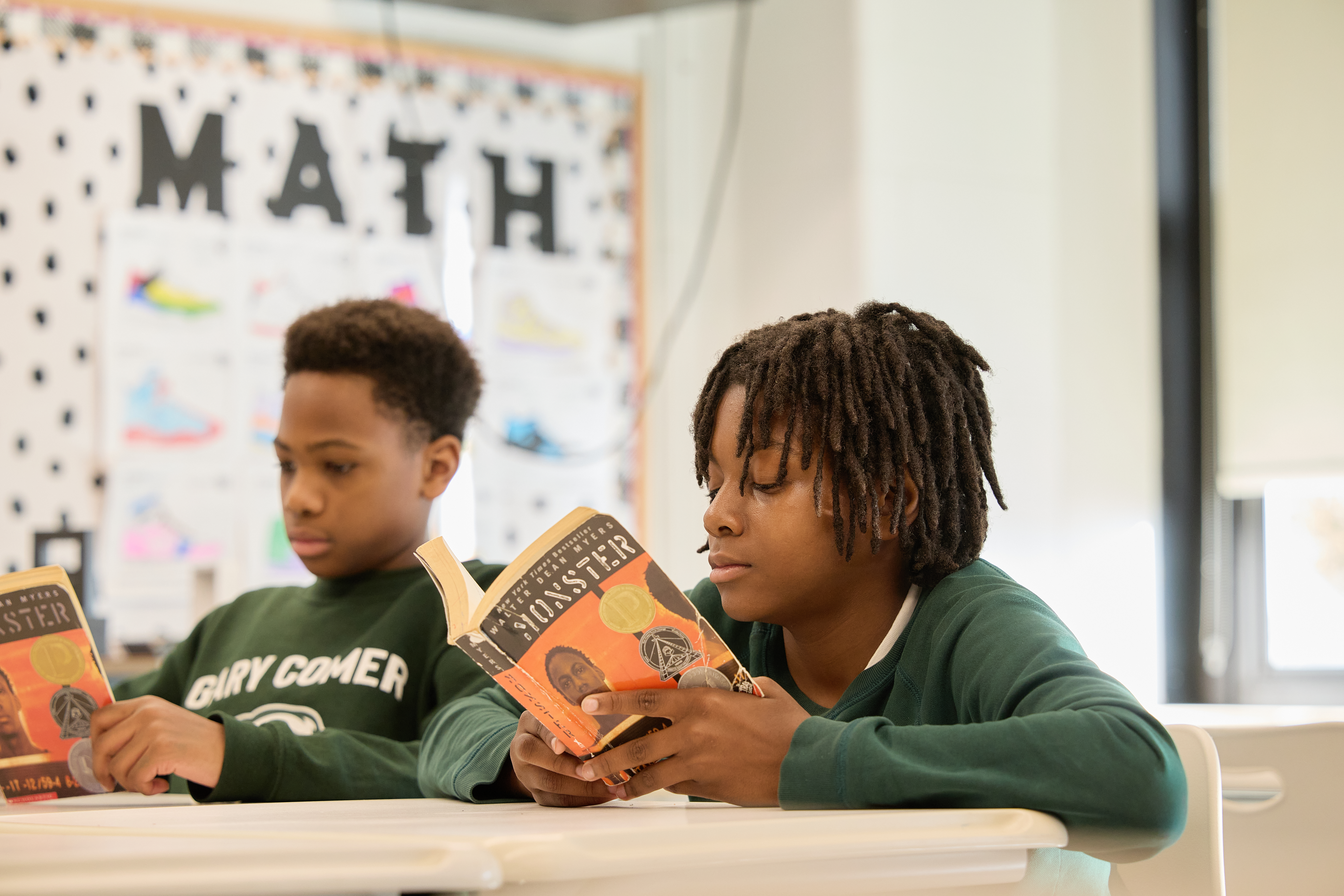 _LM_2055 Two students sit in the classroom, reading the book "Monster" by Walter Dean Myers.
