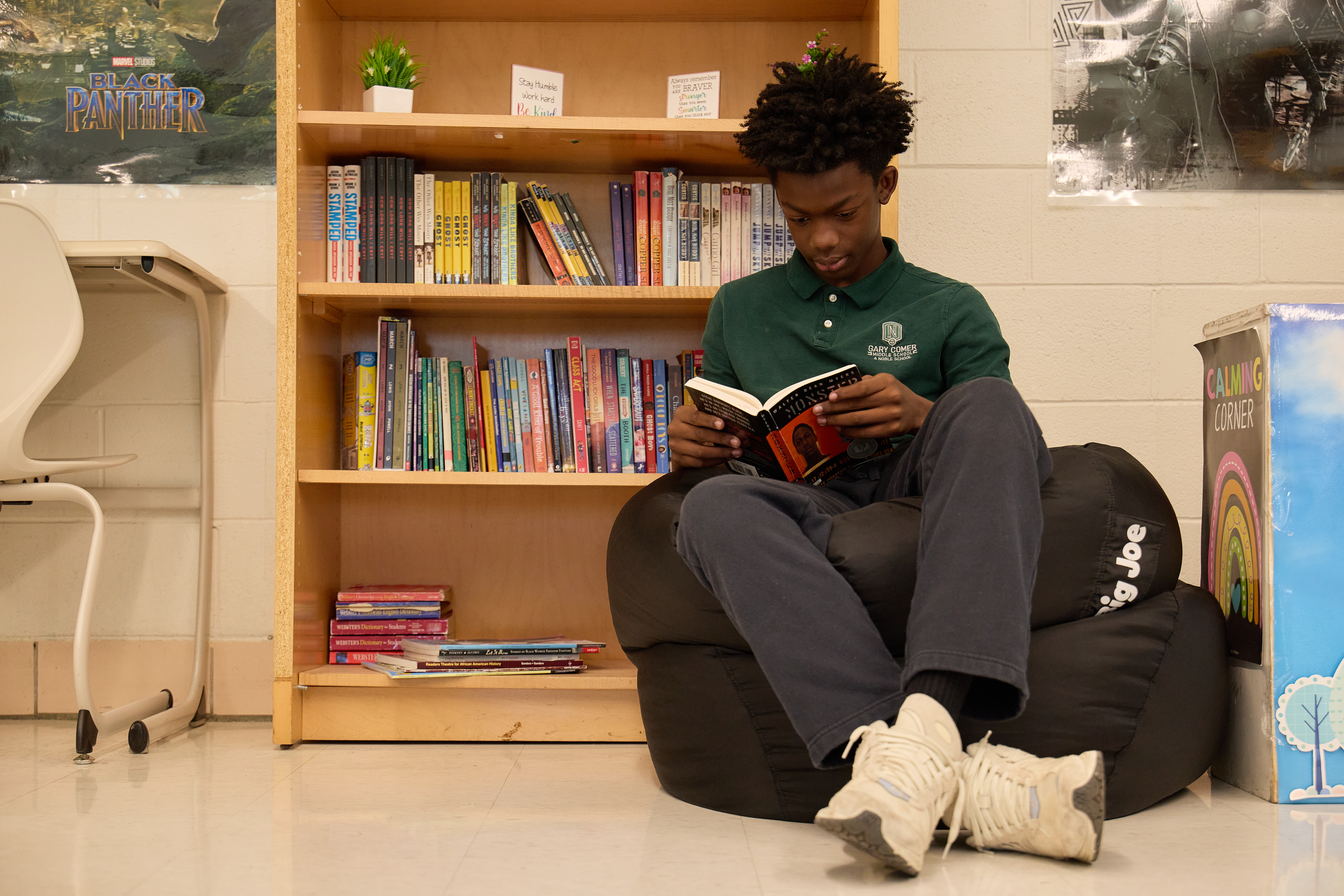_LM_2066 A Gary Comer College Prep student reads a book. He is sitting on a beanbag in a cozy nook, right in front of a bookshelf.