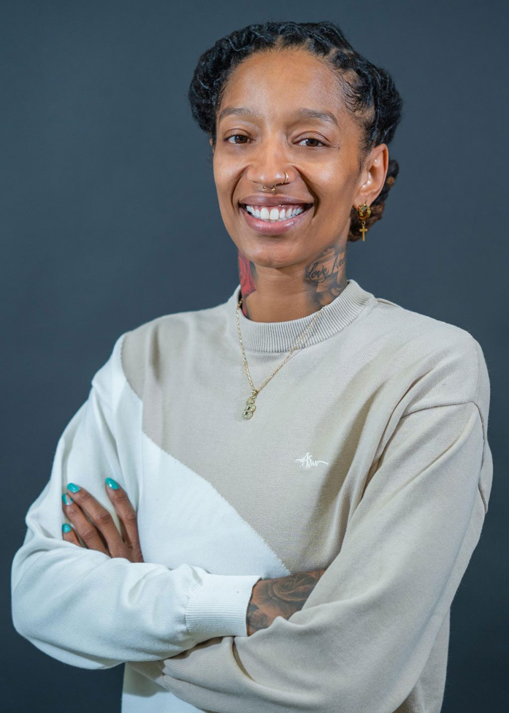 Brianna Alvarez DLF Cohort 2025 Headshot of Brianna Alavarez. She is a Black hispanic woman and short black locs that go to the back of her head. She is smiling and wearing a light brown and white sweater diagonally divided across her chest.