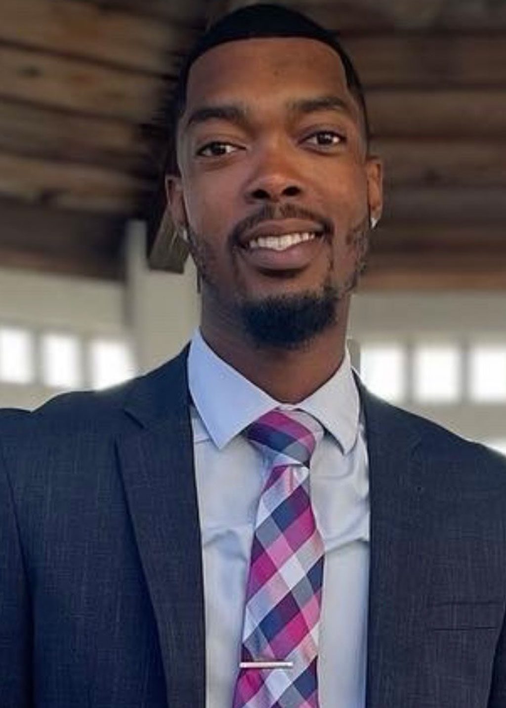 Curtis Melton DLF Cohort 2025 Headshot of Curtis Melton. He is a Black man with a black short fade haircut, light beard and goateee. He is smiling and wearing a light blue business shirt, magenta, blue and gray patterned tie with a patterned gray blazer.