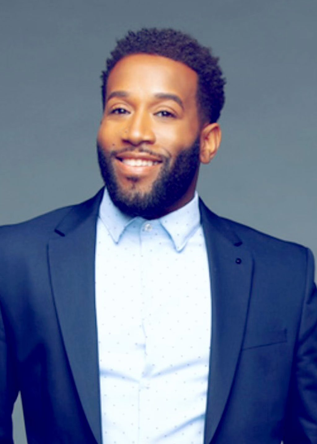 Dee Nix DLF Cohort 2025 Headshot of Dee Nix. He is a Black man with curly black hair and beard. He is smiling and wearing a light blue dotted shirt and blue navy blazer.
