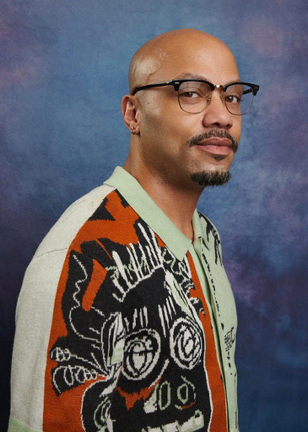 Melvin Watson Richardson DLF Cohort 2025 Headshot of Melvin Watson Richardson. He is a Black bald man with a mustache and short goatee. He is smiling and wearing a shirt with an orange and black themed artwork.