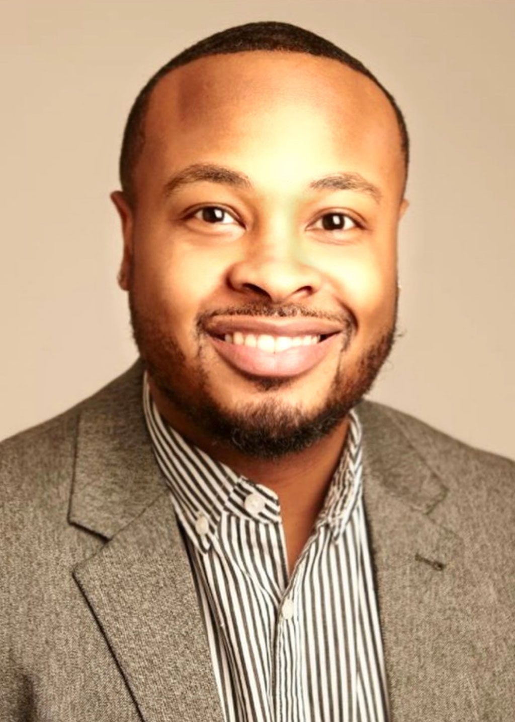Quinton Bonds DLF Cohort 2025 Headshot of Quinton Bonds. He is a Black man and short short fade hair cut scrubby thin beard. He is smiling wearing a striped black and white undershirt and gray patterned blazer.