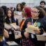 A student looks in rapt attention to an HBCU admissions counselor at Noble Schools' 2025 HBCU College Fair. She's wearing a black sweatshirt that has "HBCU" in the pan-African colors blazoned across the front.
