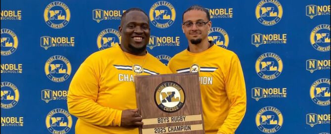 Pritzker College Prep coaches Jovon Hernandez and Anthony Johnson pose for a photo, holding a plaque between them. The plaque says “Boys Rugby 2025 Champions”.