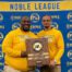 Pritzker College Prep coaches Jovon Hernandez and Anthony Johnson pose for a photo, holding a plaque between them. The plaque says “Boys Rugby 2025 Champions”.