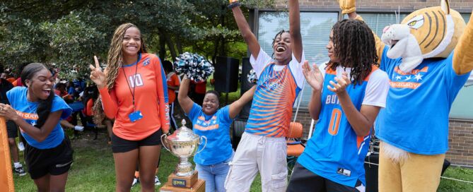 Butler College Prep athletes and their Lynx mascot are cheering as they present the giant Noble League Cup trophy.