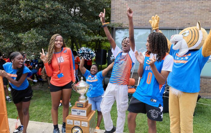 Butler College Prep athletes and their Lynx mascot are cheering as they present the giant Noble League Cup trophy.