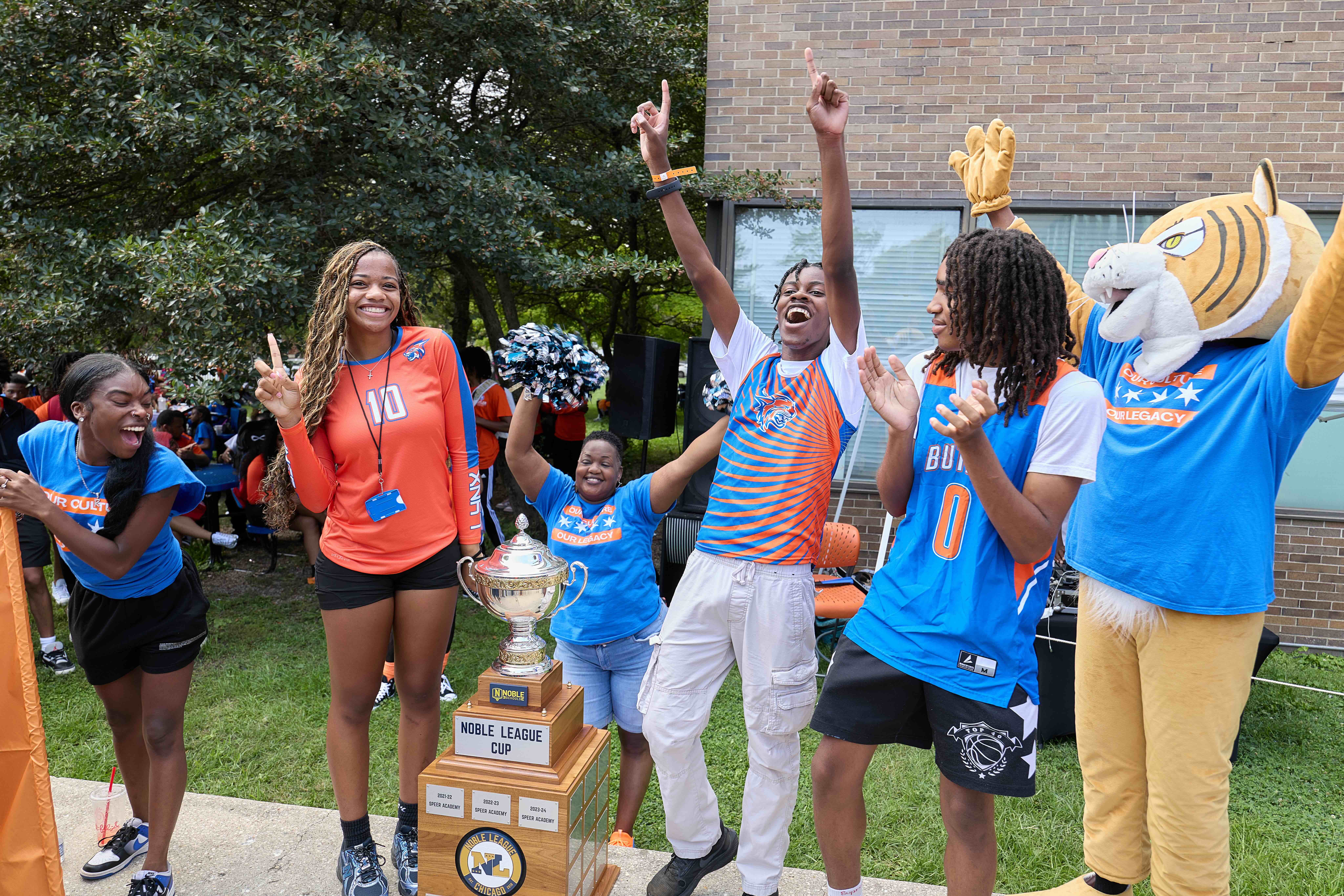 Butler College Prep athletes and their Lynx mascot are cheering as they present the giant Noble League Cup trophy.