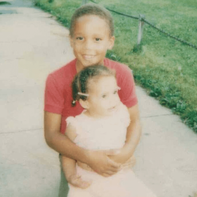 image1 Carew's brother hugs her from behind, smiling.