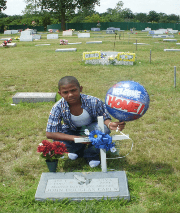 image3 Jillian Carew's nephew kneels over his father's gravestone with a memorial balloon in his hand.